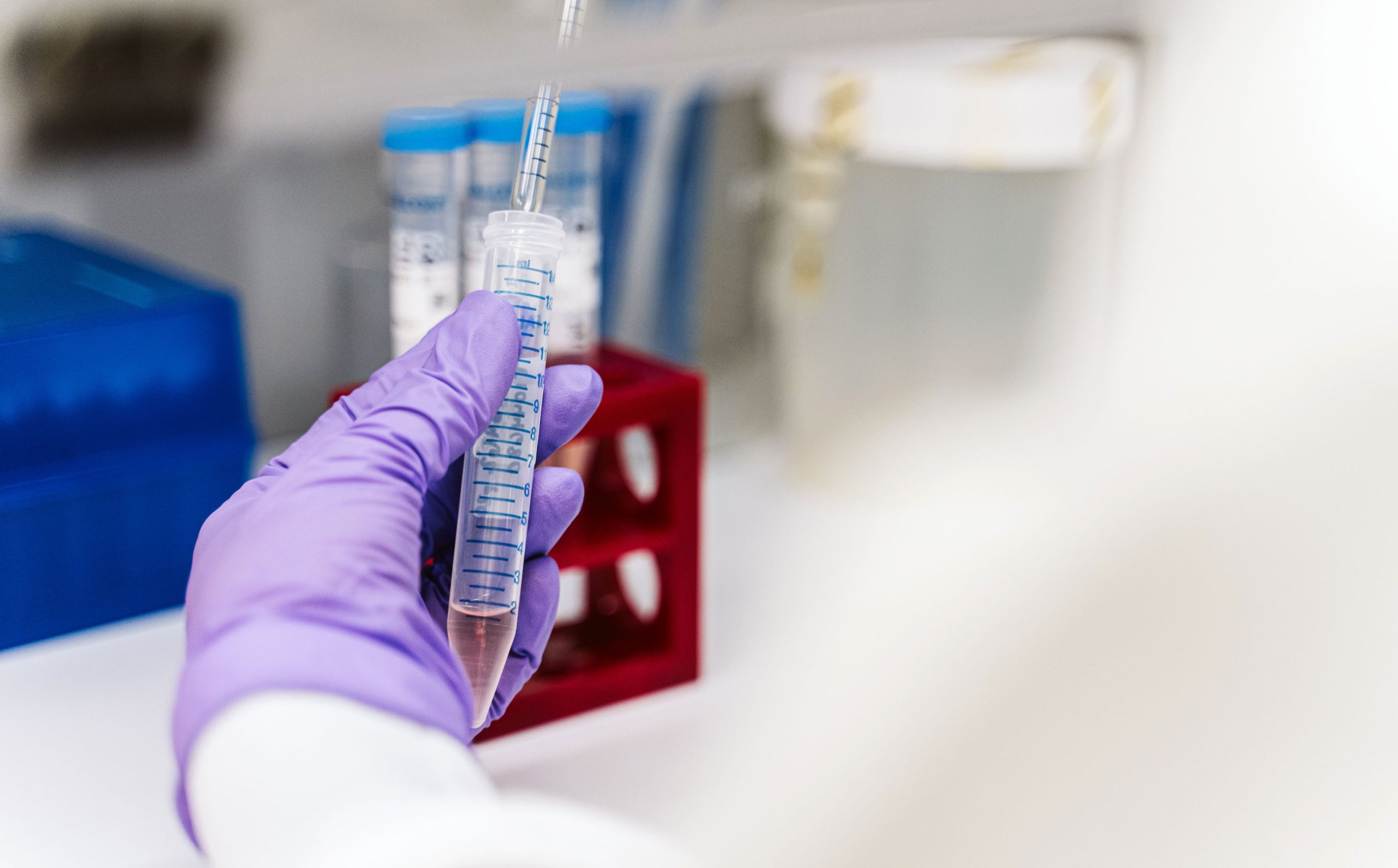 A pipette deposits a biological sample in a vial.