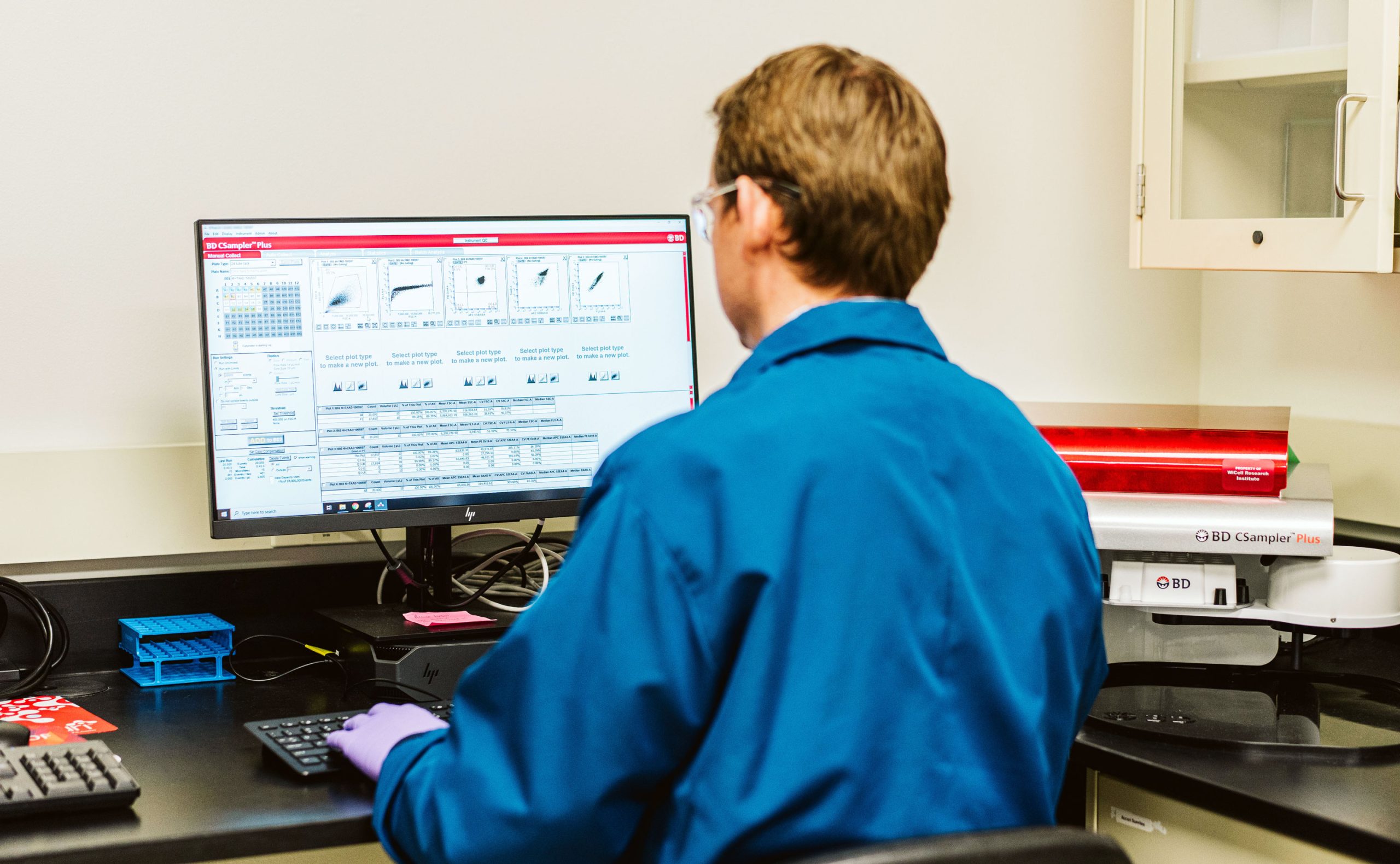 A scientist analyzes test results on a computer screen in a lab.