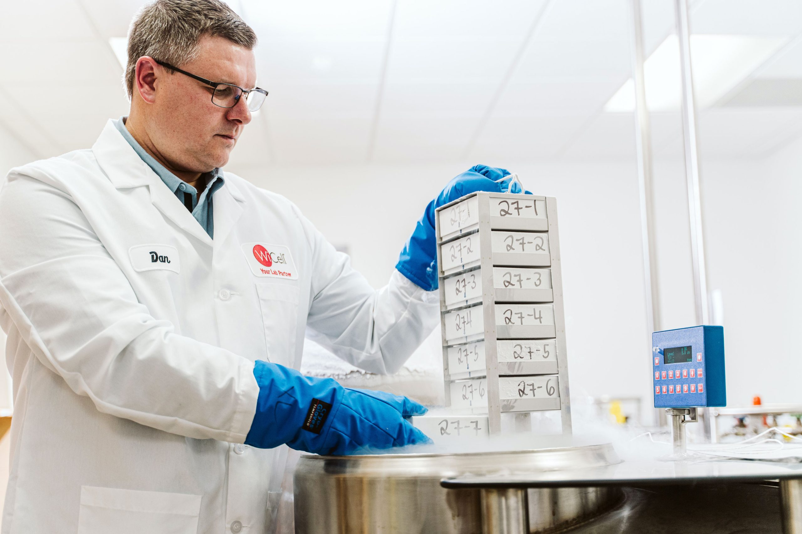 A scientist removes a box of biological samples from a cold storage vat.
