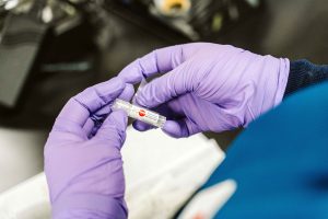 A pair of gloved hands place a label on a small WiCell vial containing human embryonic stem cells.