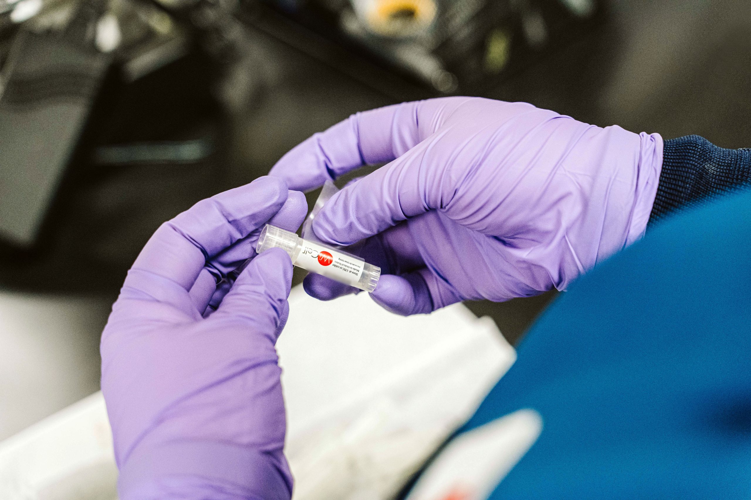 A pair of gloved hands place a label on a small WiCell vial containing human embryonic stem cells.