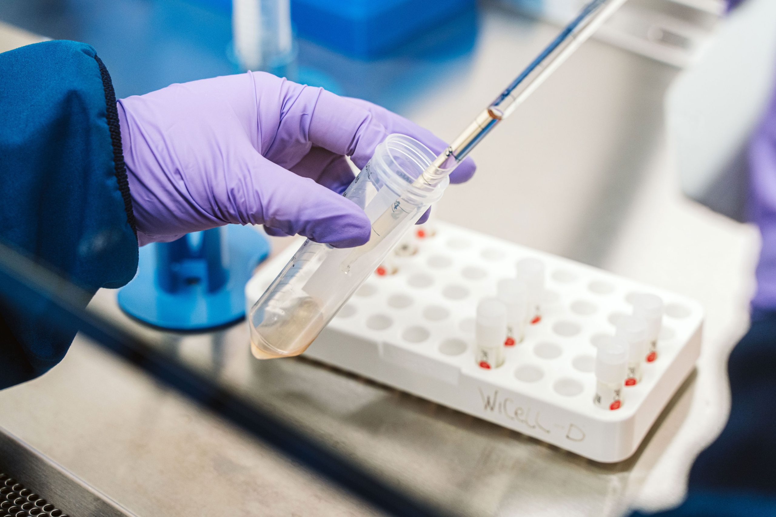 A pipette deposits a sample in a large vial.